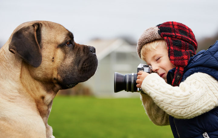 Kleiner Junge mit Kamera fotografiert seinen Hund